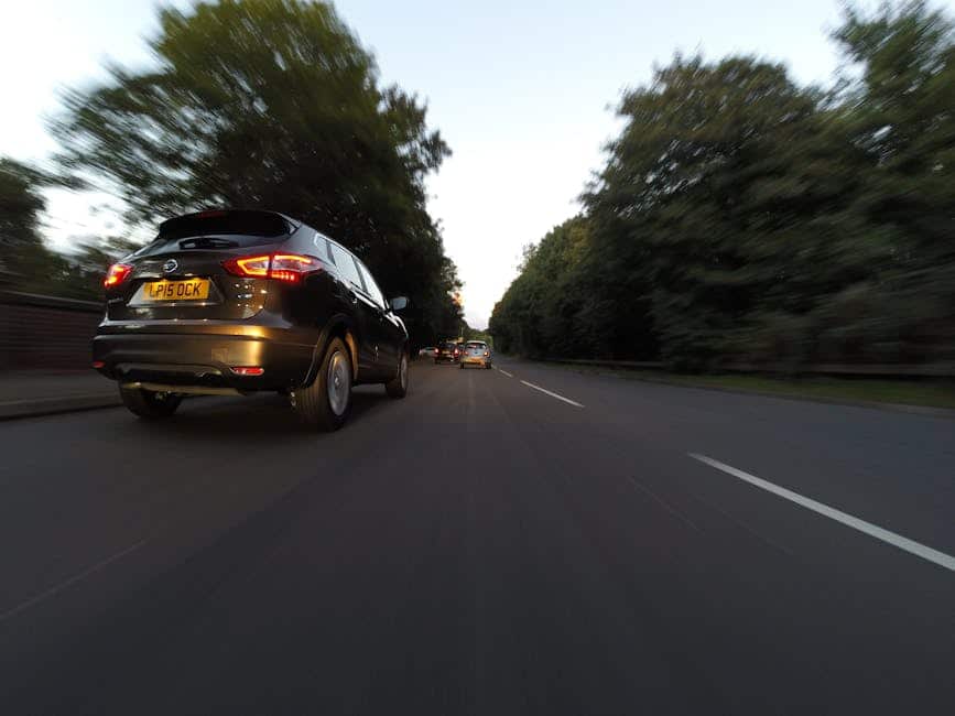 UK hire car - cars cruising on tree-lined road at dusk