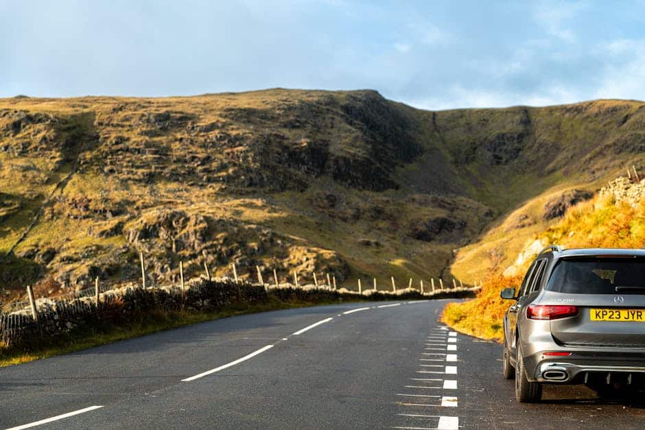 UK hire car - scenic mountain road with parked car during autumn