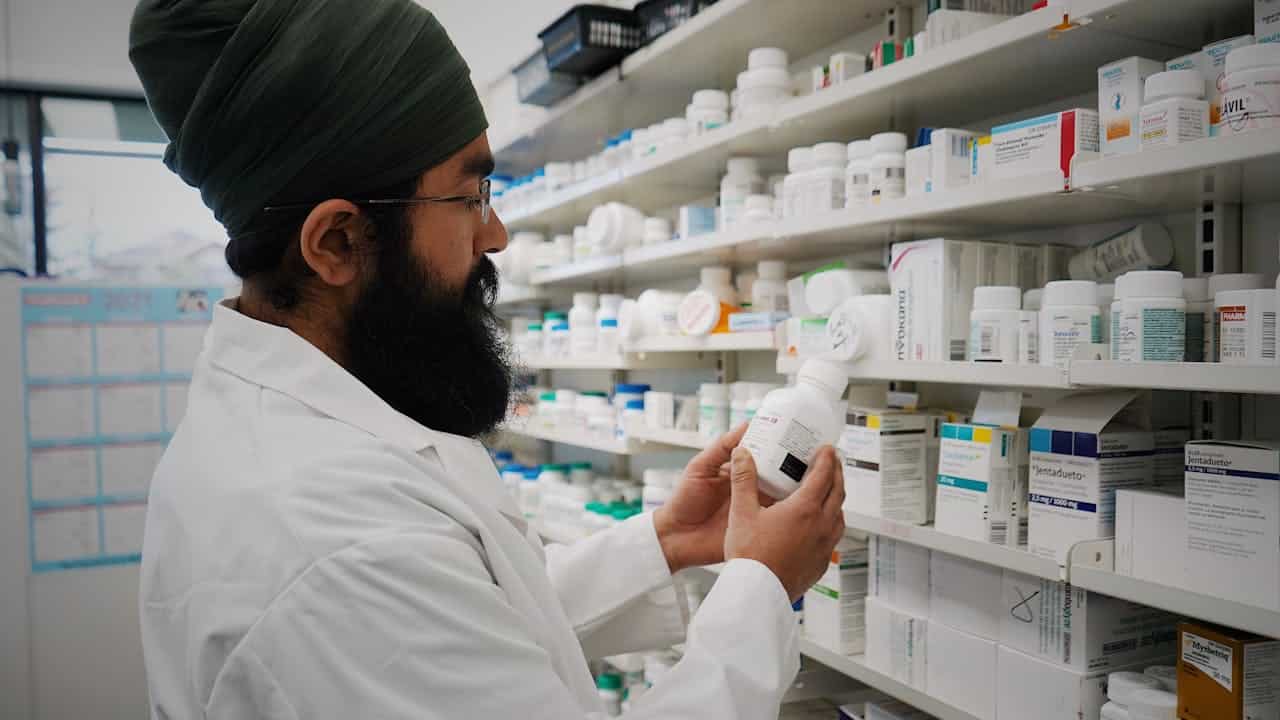 Apteekari järjestää Yhdistyneen kuningaskunnan apteekin hyllyjä uusimiseen