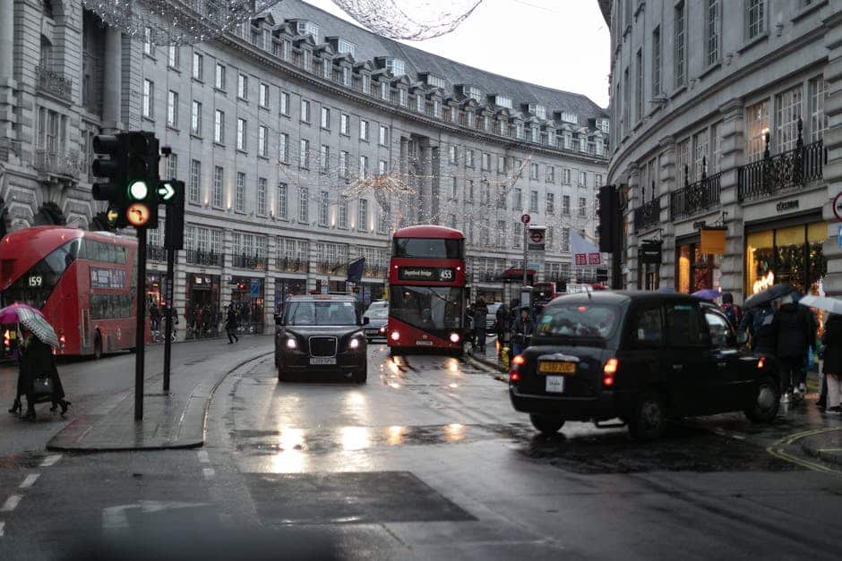 Londonska ulična scena pod delno oblačnim nebom s ljudi, ki nosijo dežnike, rdeči avtobusi in georgijanski objekti
