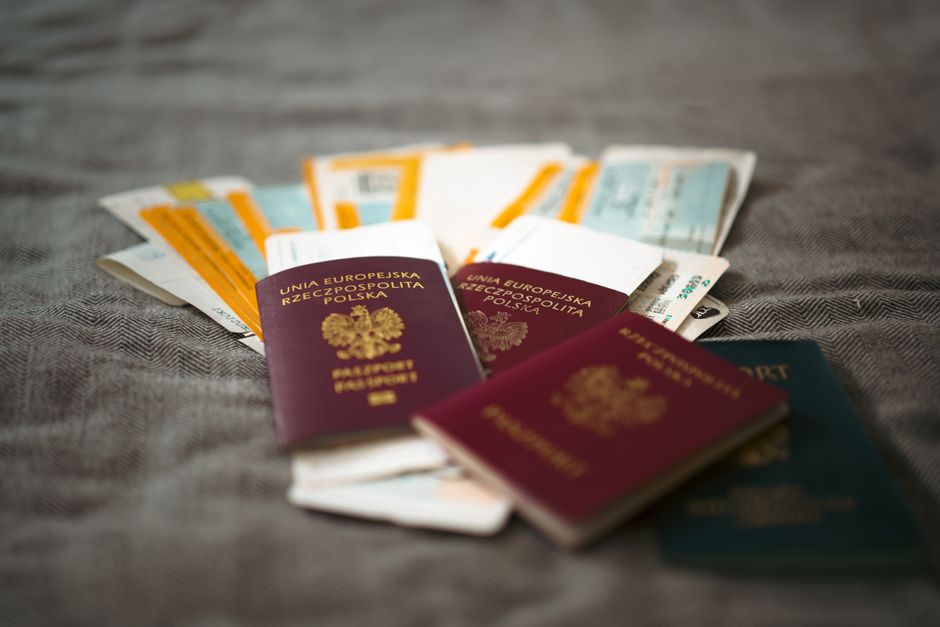 Matkustaja Britannian lentoaseman rajavalvontaalueella, e-portit ja opasteet näkyvissä, passaportti kädessä