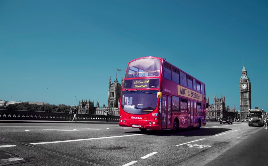 حافلة لندن حمراء ذات طابقين تعبر جسر وستمنستر مع عجلة لندن (London Eye) مرئية في الخلفية