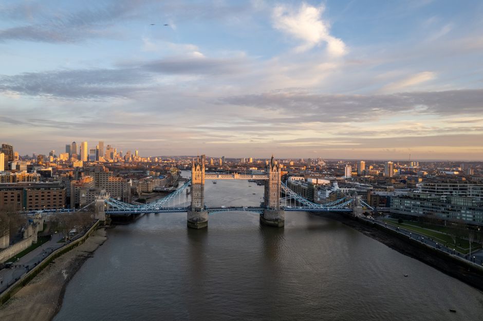 Eine helle Tagesaufnahme der Themse mit der Tower Bridge und der Skyline der City of London im Hintergrund,...