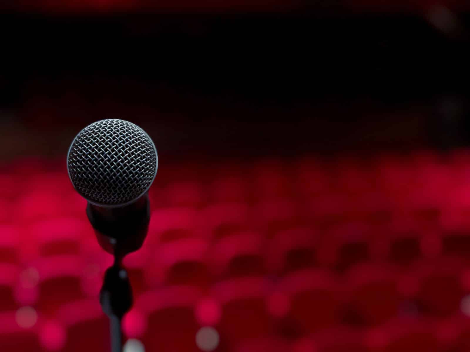 Koomikko pitelee mikrofoonia näyttämöllä stand-up-komiikkaesityksessä festivaalilla