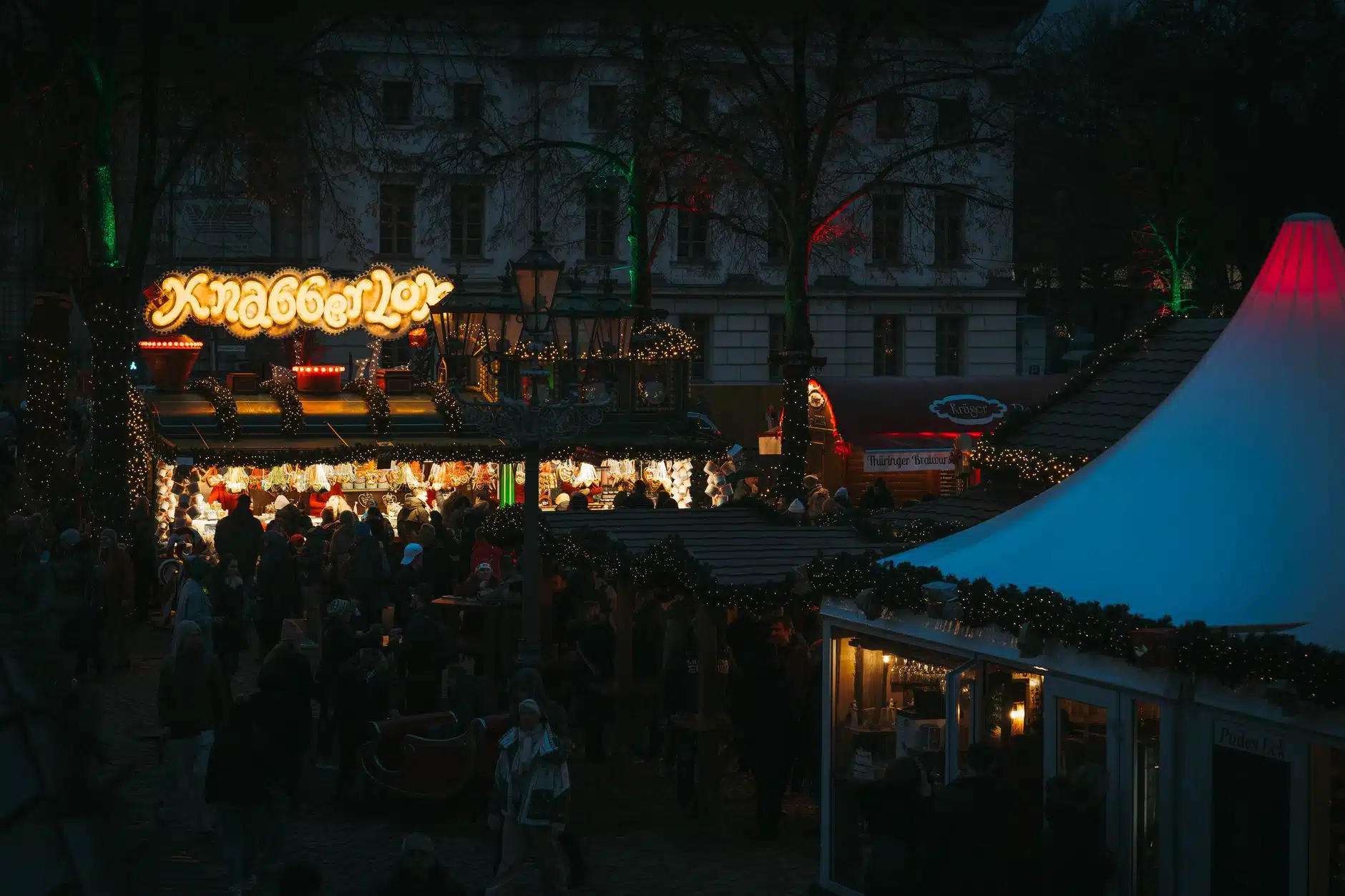 Festive crowd browsing an illuminated UK Christmas market in the evening