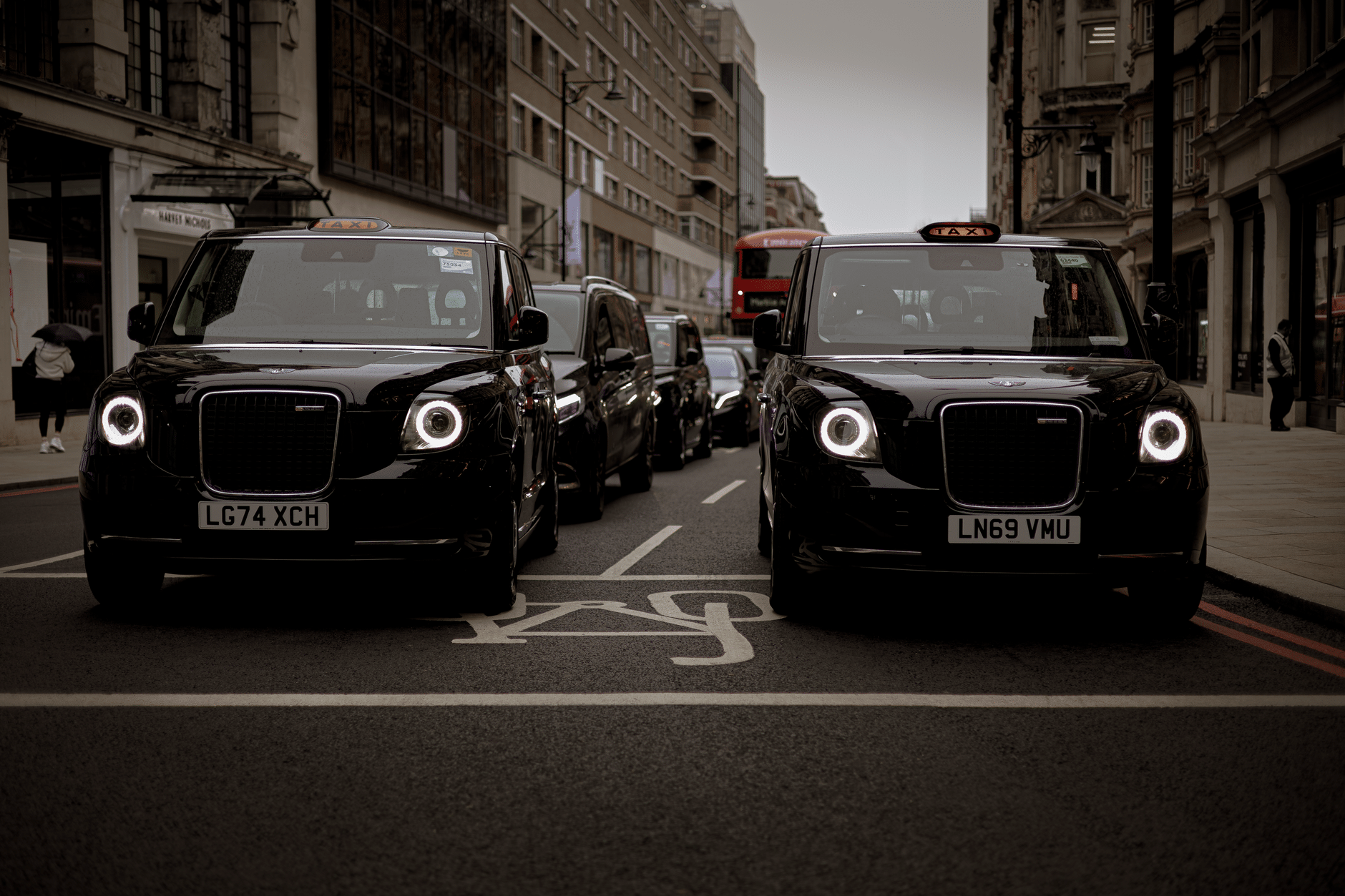 Black London taxi cab driving along a central London street near landmarks