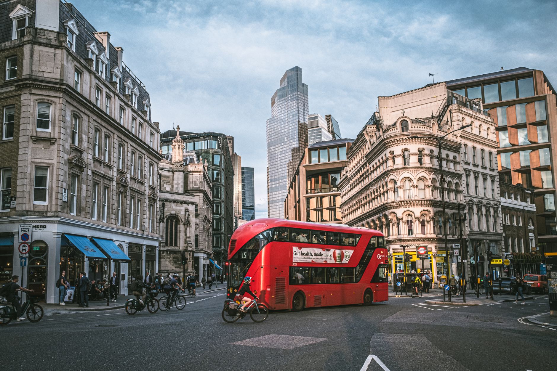 Red double-decker bus crossing a London street with the city skyline behind