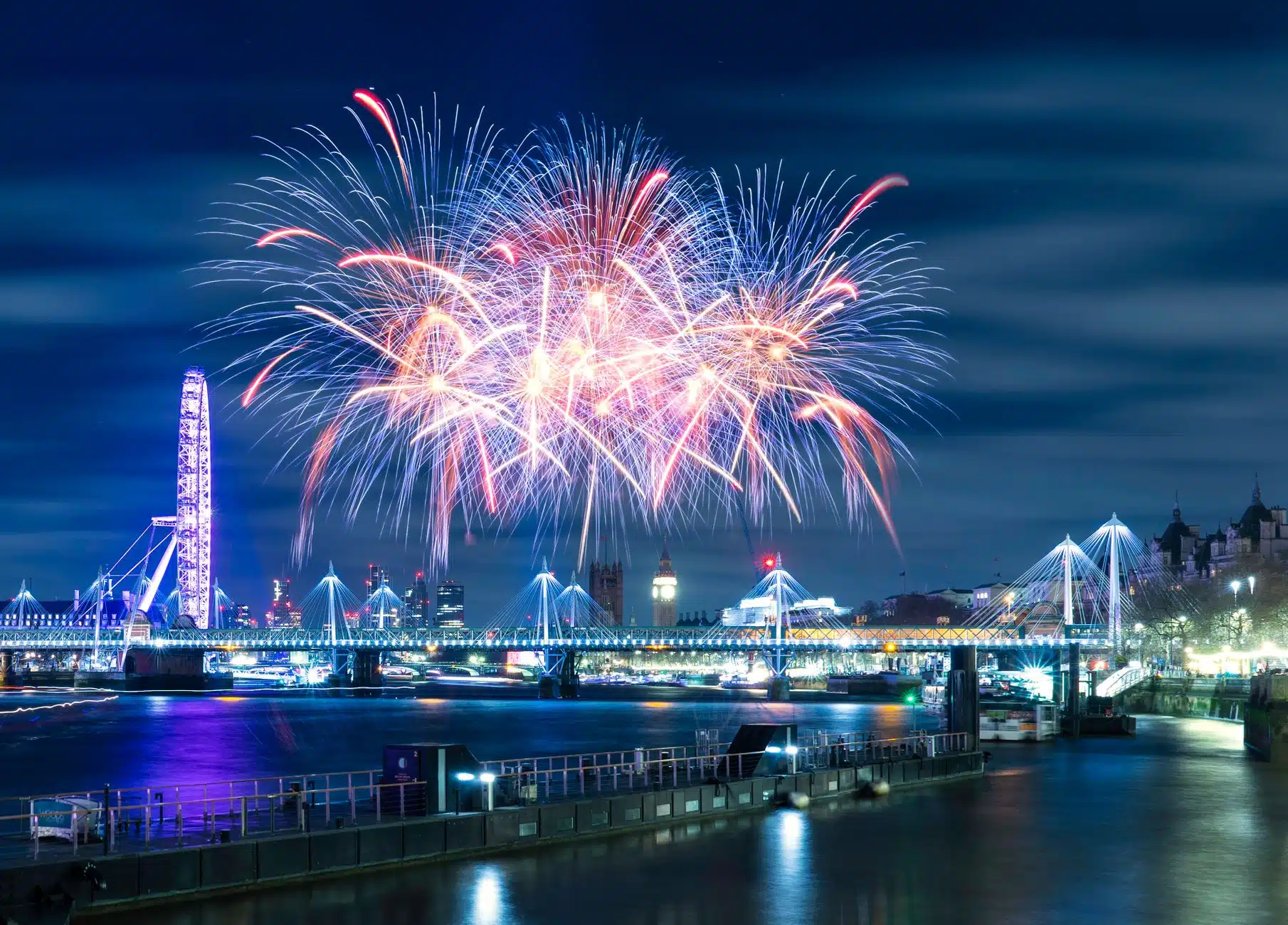 New Year fireworks bursting over the River Thames and London Eye at midnight